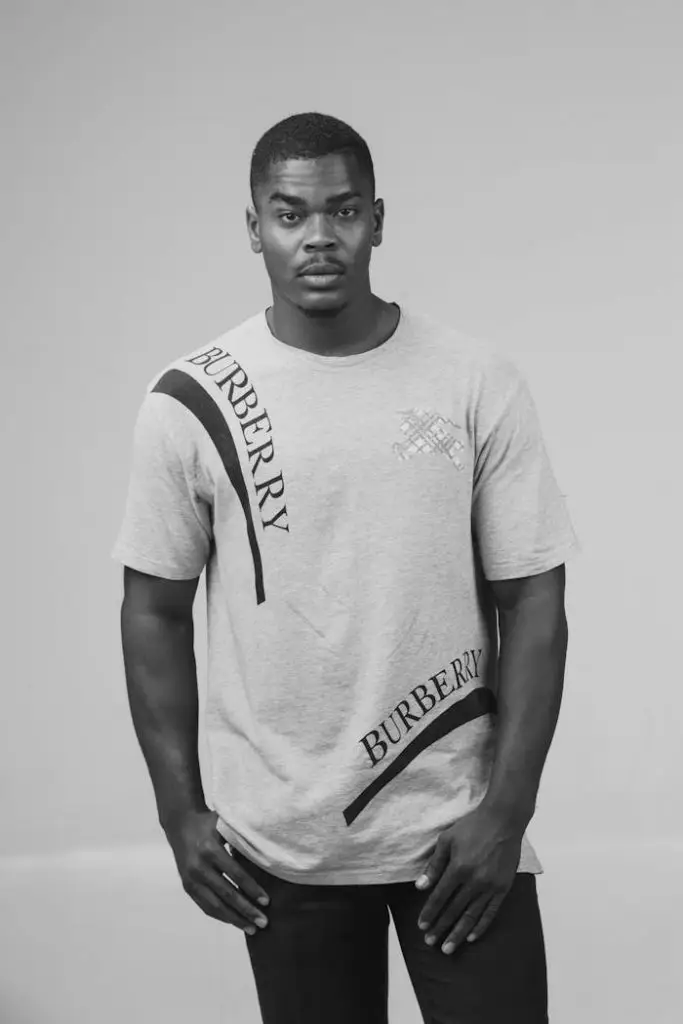 Stylish black and white portrait of a man wearing a branded Burberry t-shirt, exuding confidence.