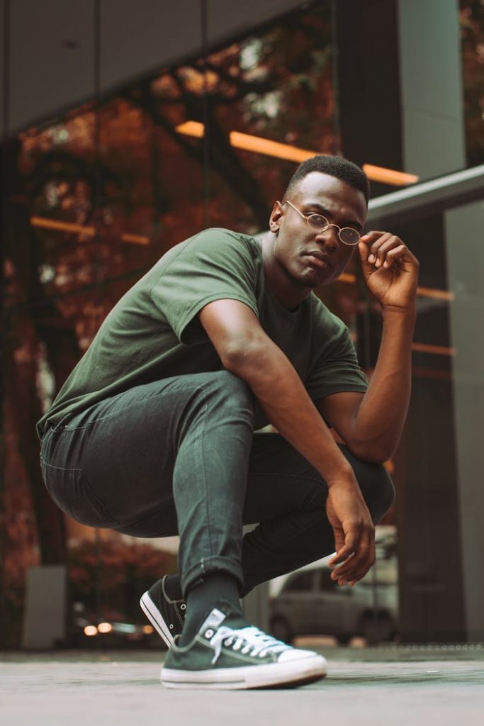 A contemporary portrait of a young man posing confidently outdoors with vibrant green tones.