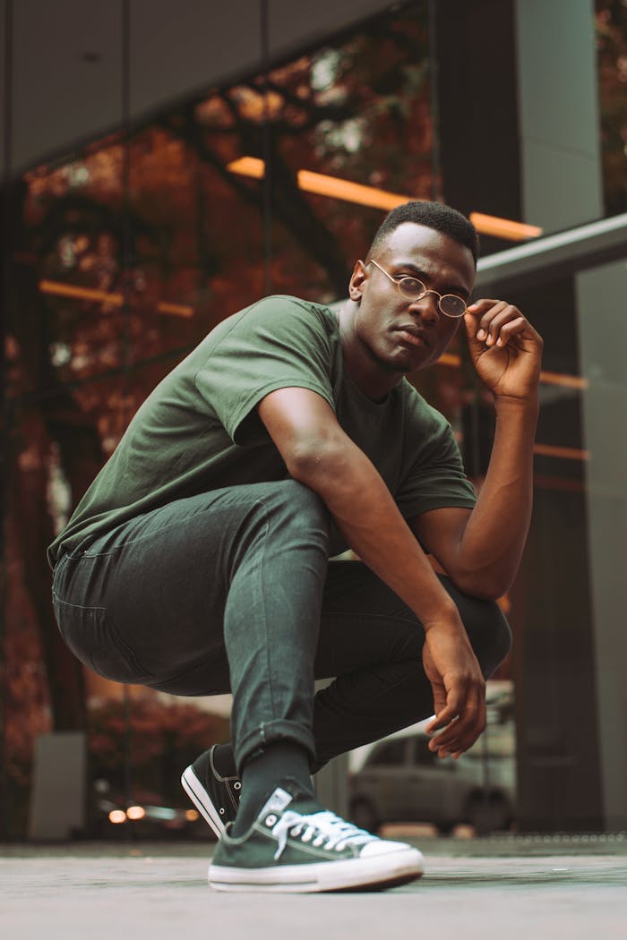 A contemporary portrait of a young man posing confidently outdoors with vibrant green tones.